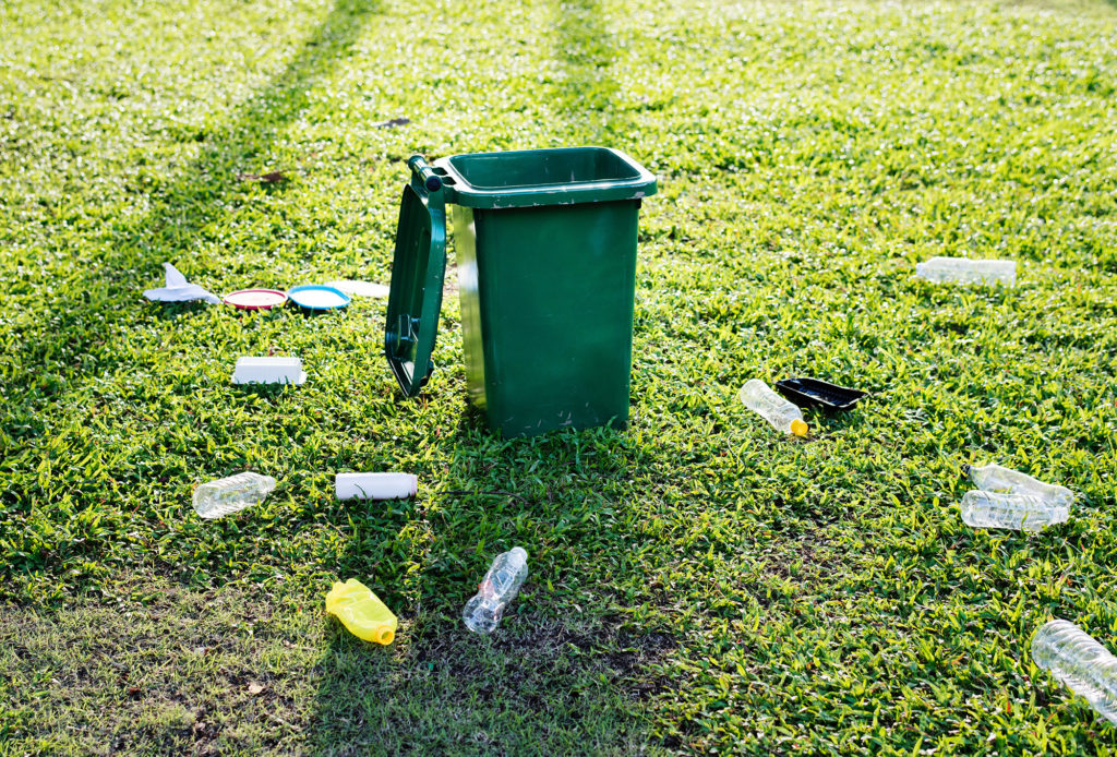 trash on ground around a trash can