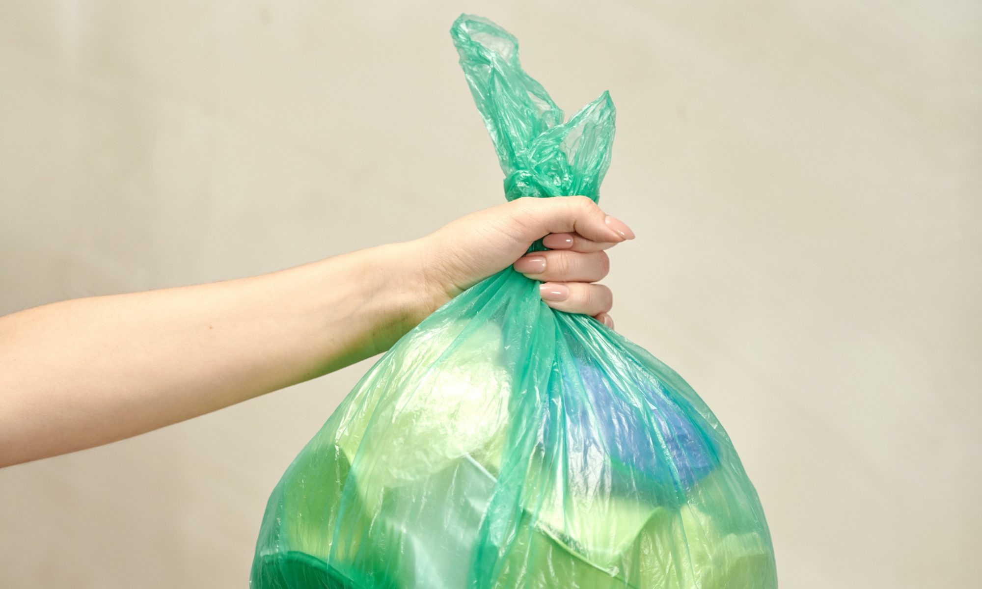 arm and hand holding a plastic bag of trash