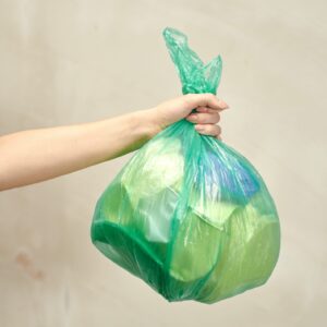 arm and hand holding a plastic bag of trash