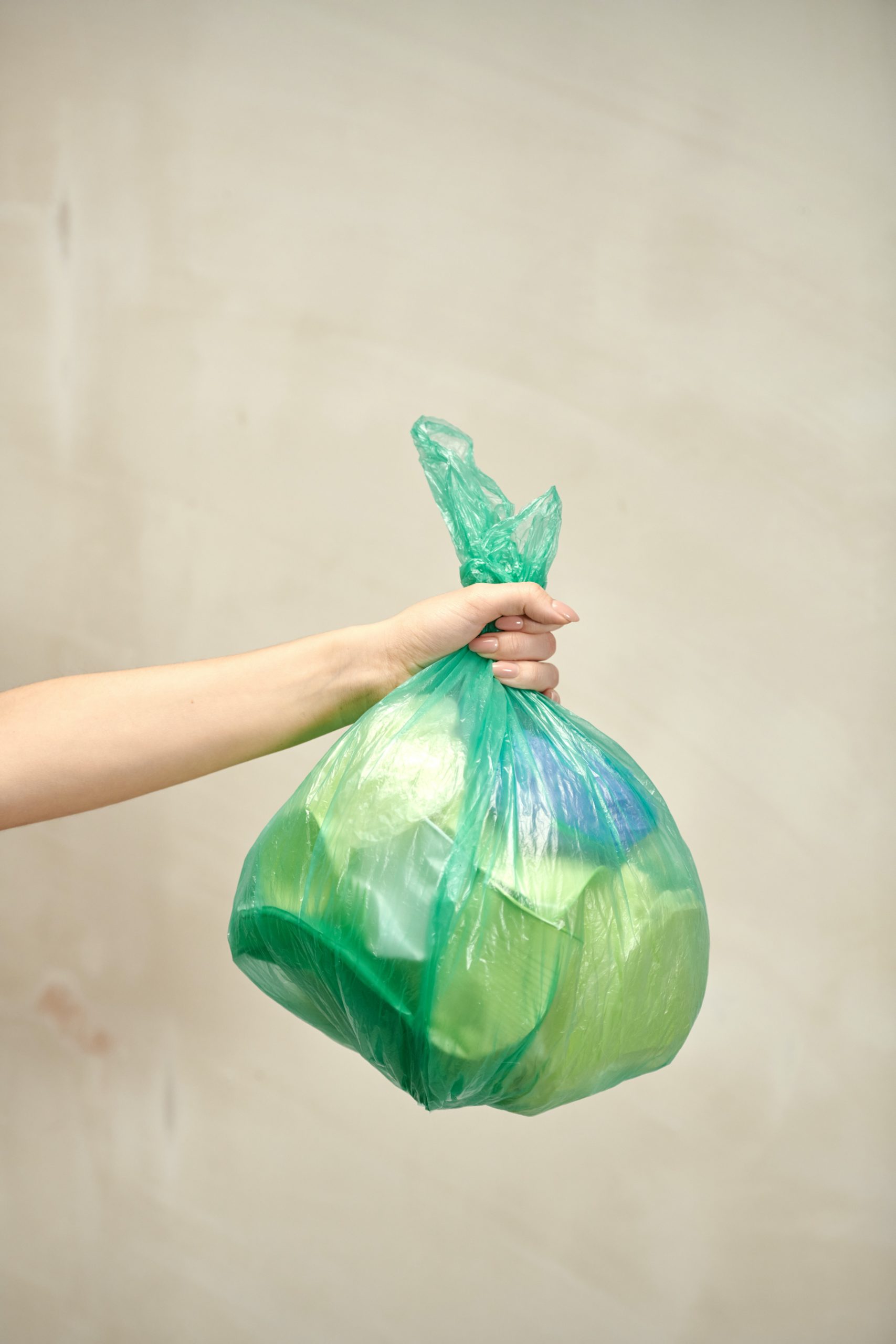 arm and hand holding a plastic bag of trash